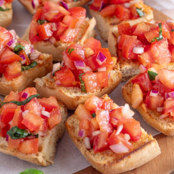 A board of gluten free bruschetta topped with tomatoes.