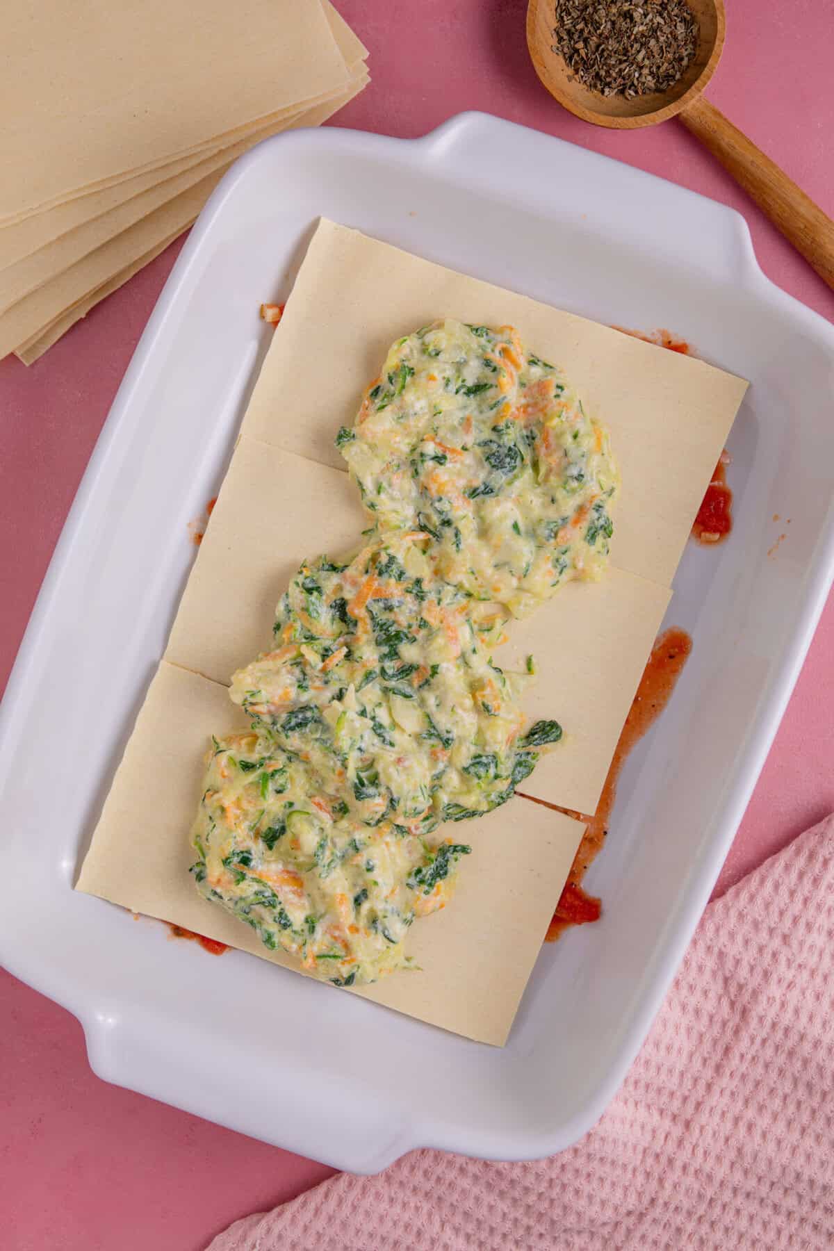 Gluten free courgette lasagne recipe process shot showing a layer of sauce, then lasagne sheets, then the courgette layer.