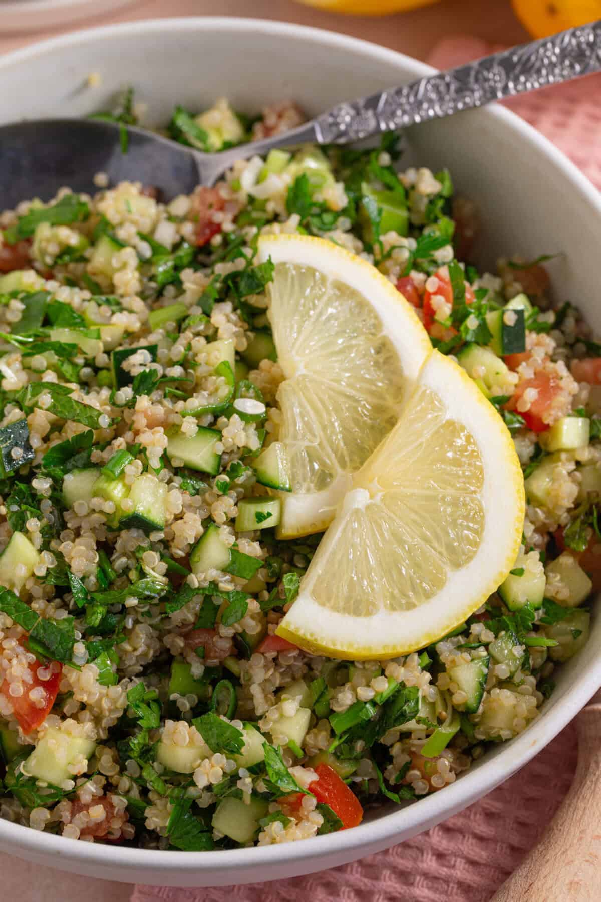 A bowl of gluten free tabbouleh with lemon slices on top.
