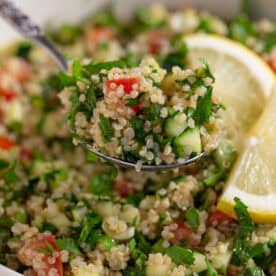 A spoon lifting out a portion of gluten free tabbouleh from a bowl.