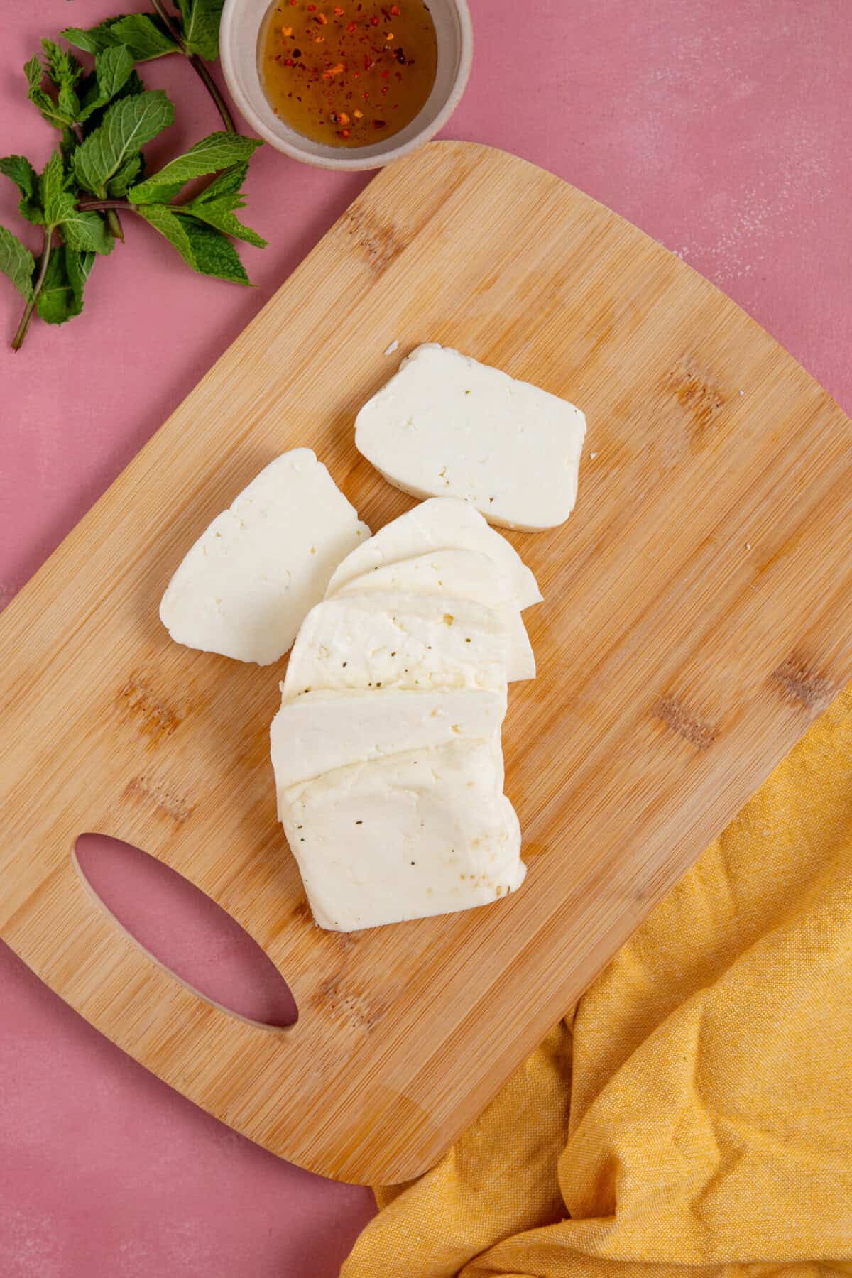 Process shot of peach and halloumi salad recipe showing the halloumi cut into slices on a board.
