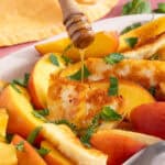 Hot honey being drizzled over slices of peach and grilled halloumi.