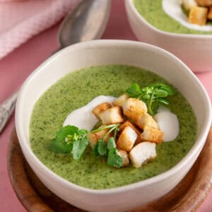 A bowl of watercress soup topped with creme fraiche and croutons.