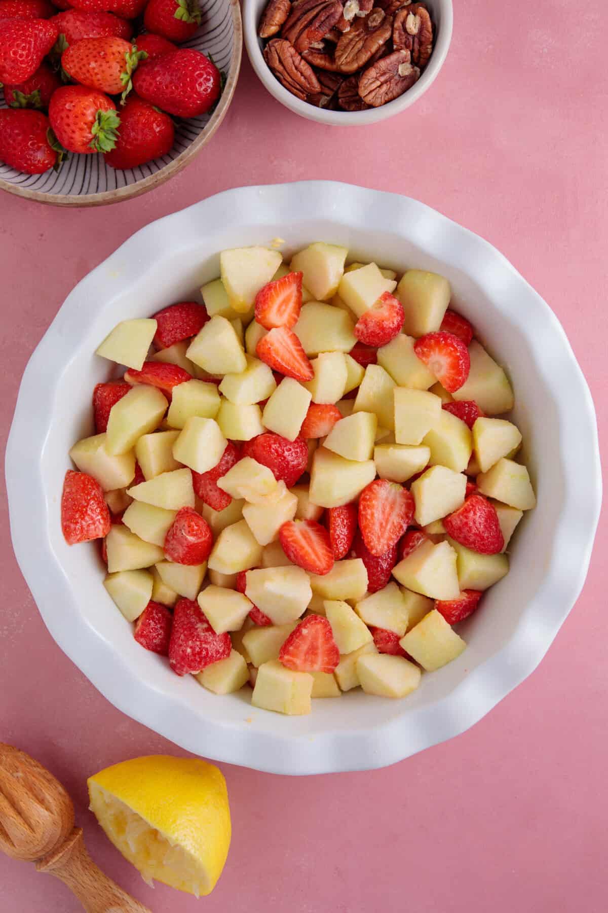 Process shot for apple and strawberry crumble recipe showing the apples and strawberries in a dish.