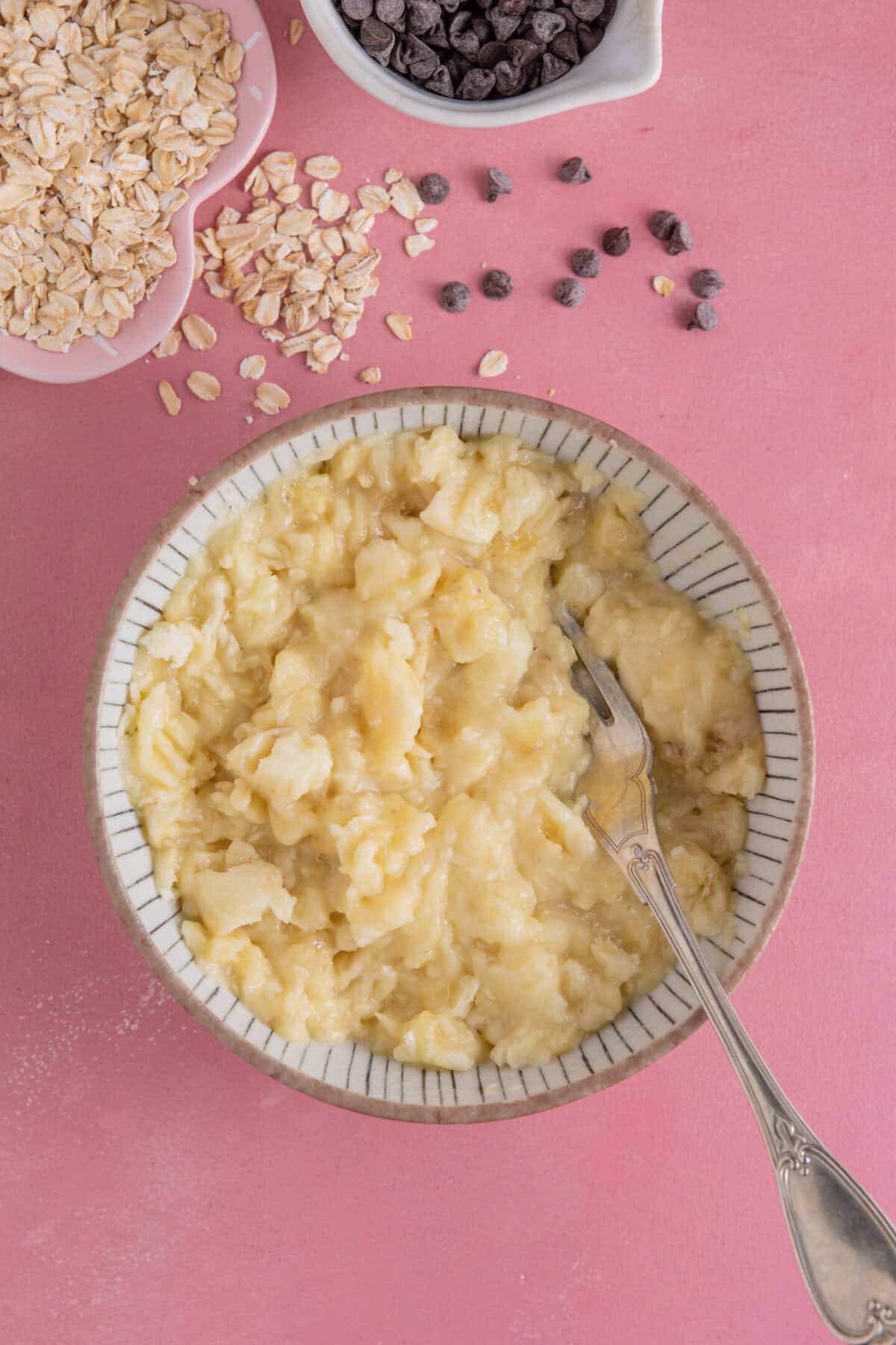 Process shot of banana baked oats showing mashed banana in a bowl.