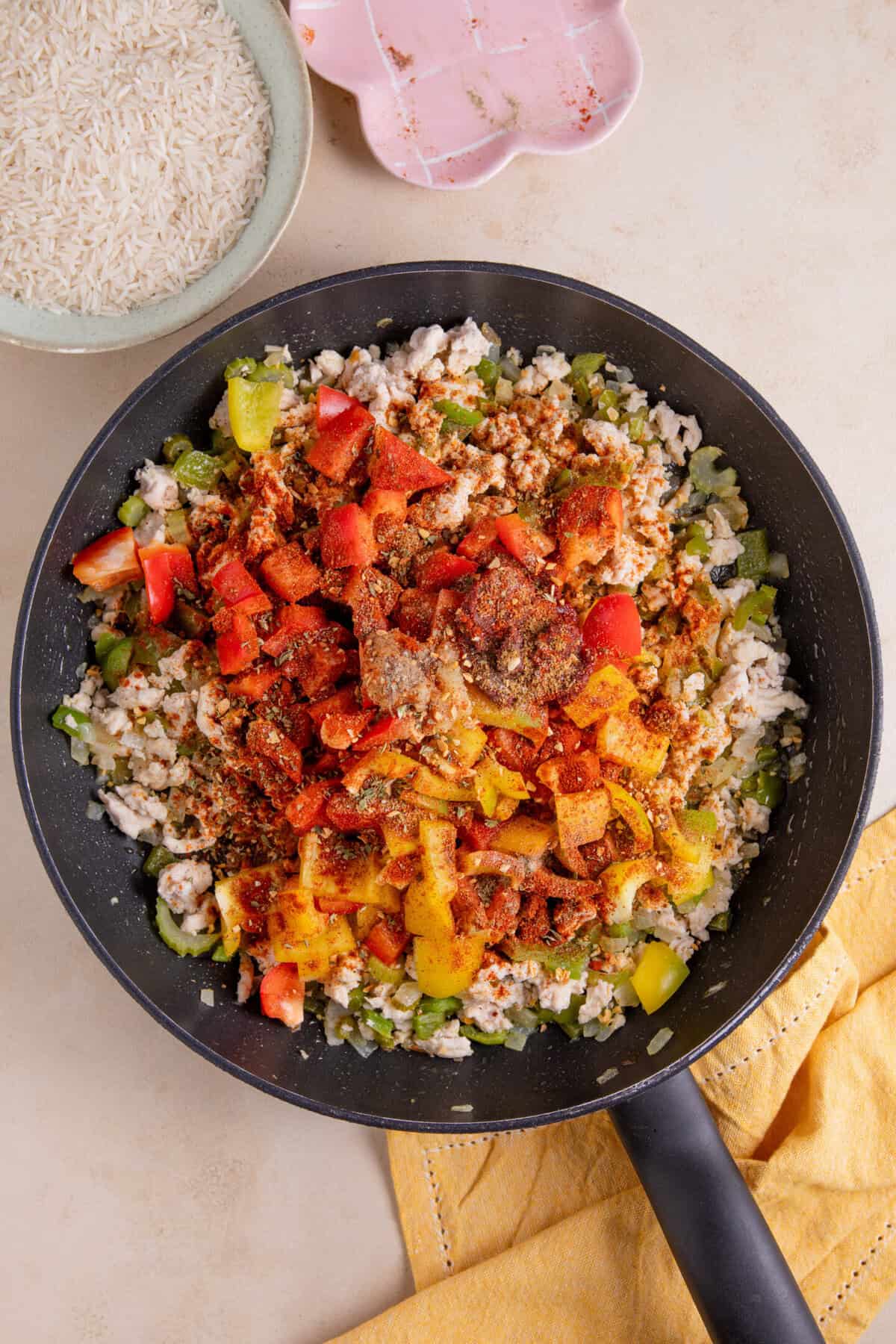 Process shot of cajun rice recipe showing the pan full of peppers, spices, chicken mince, onions and celery.