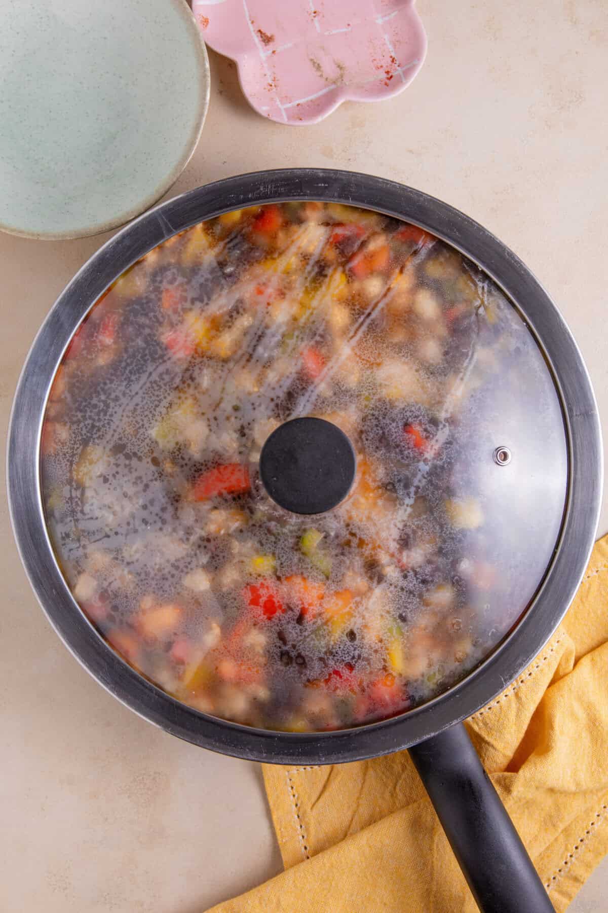 Process shot of cajun rice recipe in a pan covered with a lid.