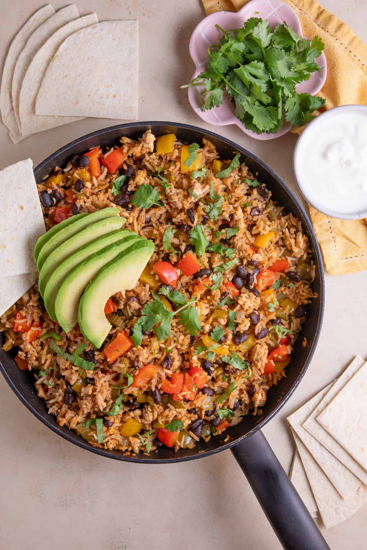 A pan of Cajun rice with avocado and tortilla chips.