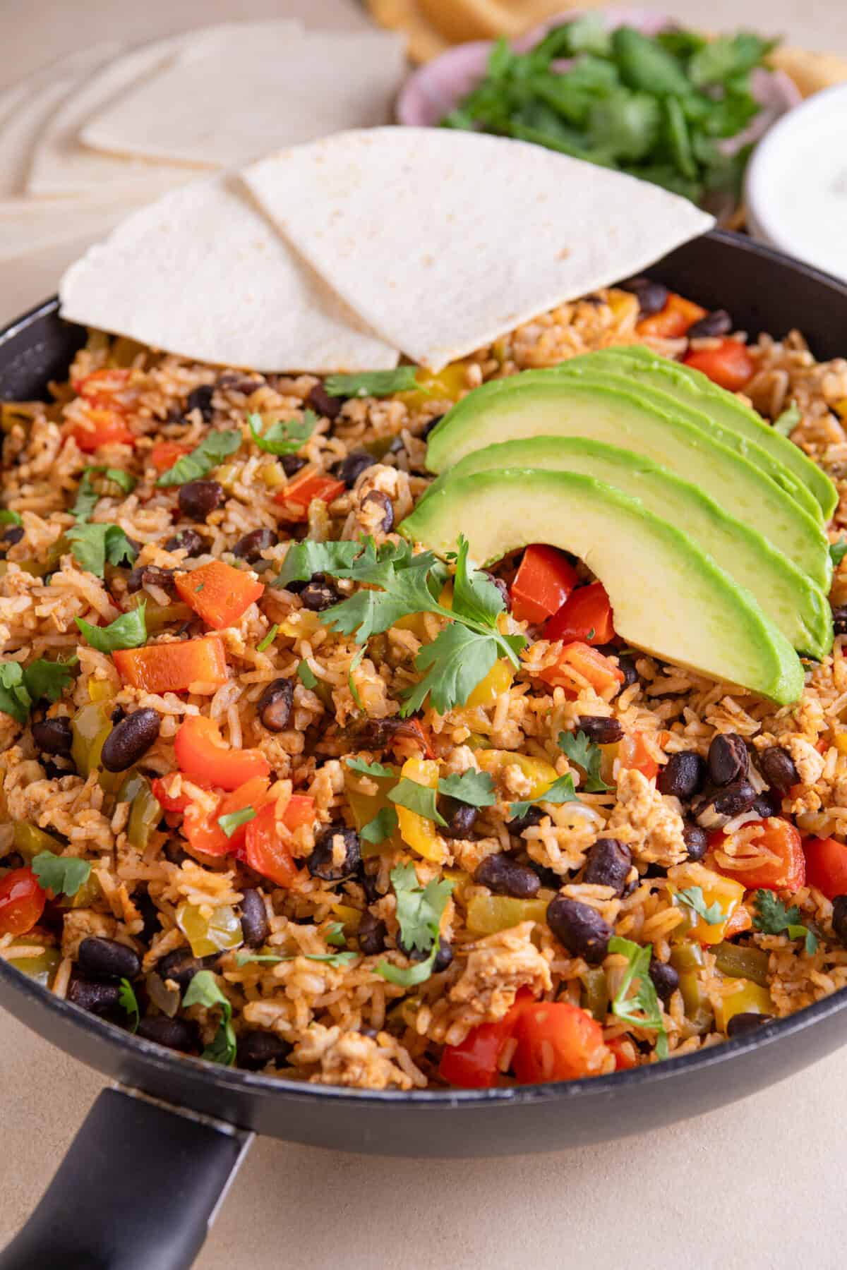 Close up of a pan of cajun rice topped with avocado and tortilla chips.