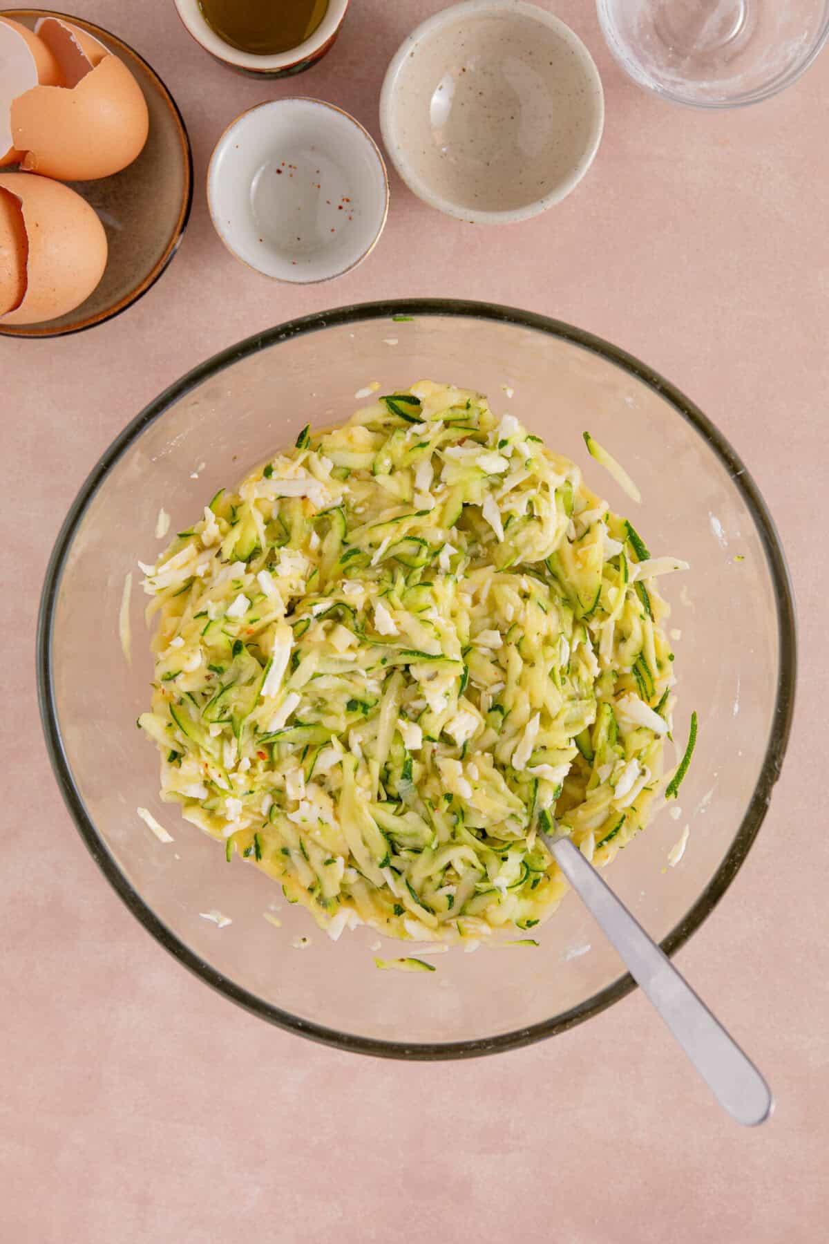 Process shot of courgette and halloumi fritters showing the mixture in a bowl before making intro fritters.