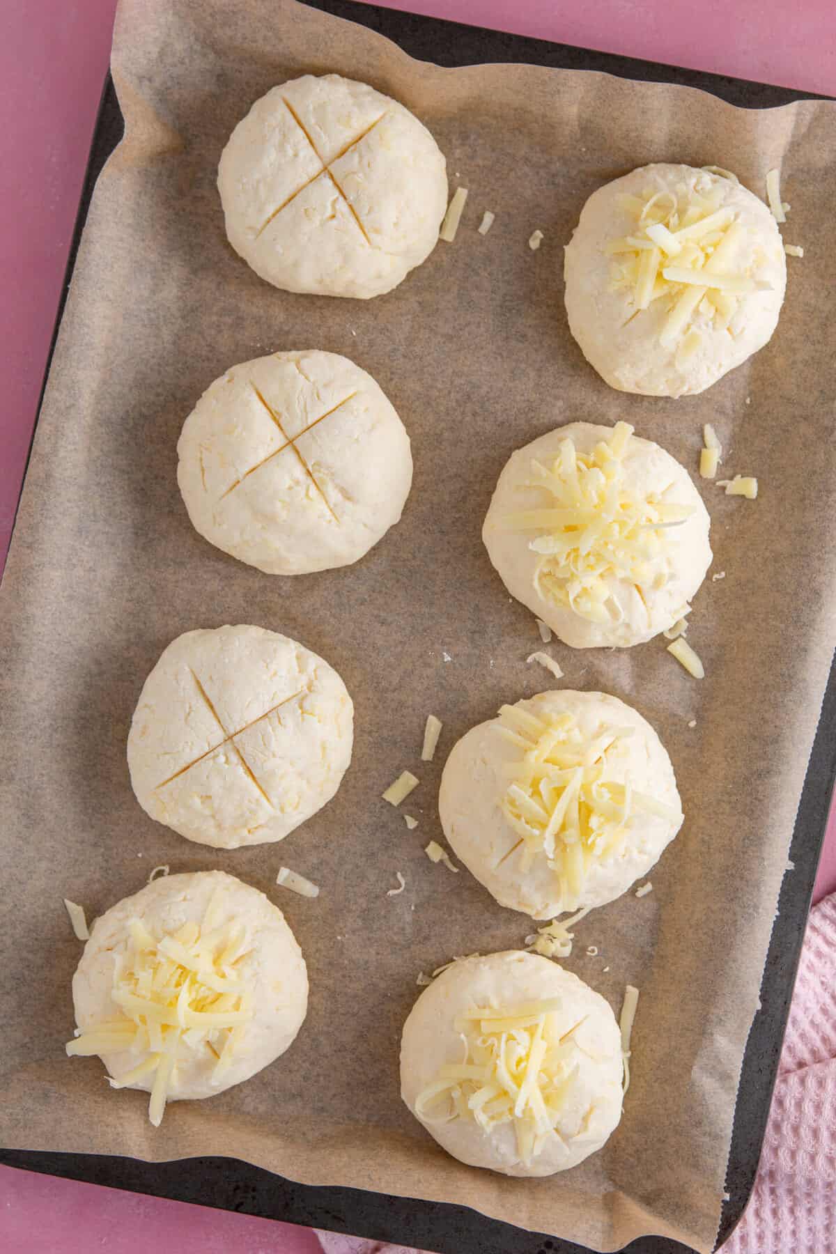 Process shot of gluten free cheese bread rolls showing the dough shaped into rolls on a baking sheet.