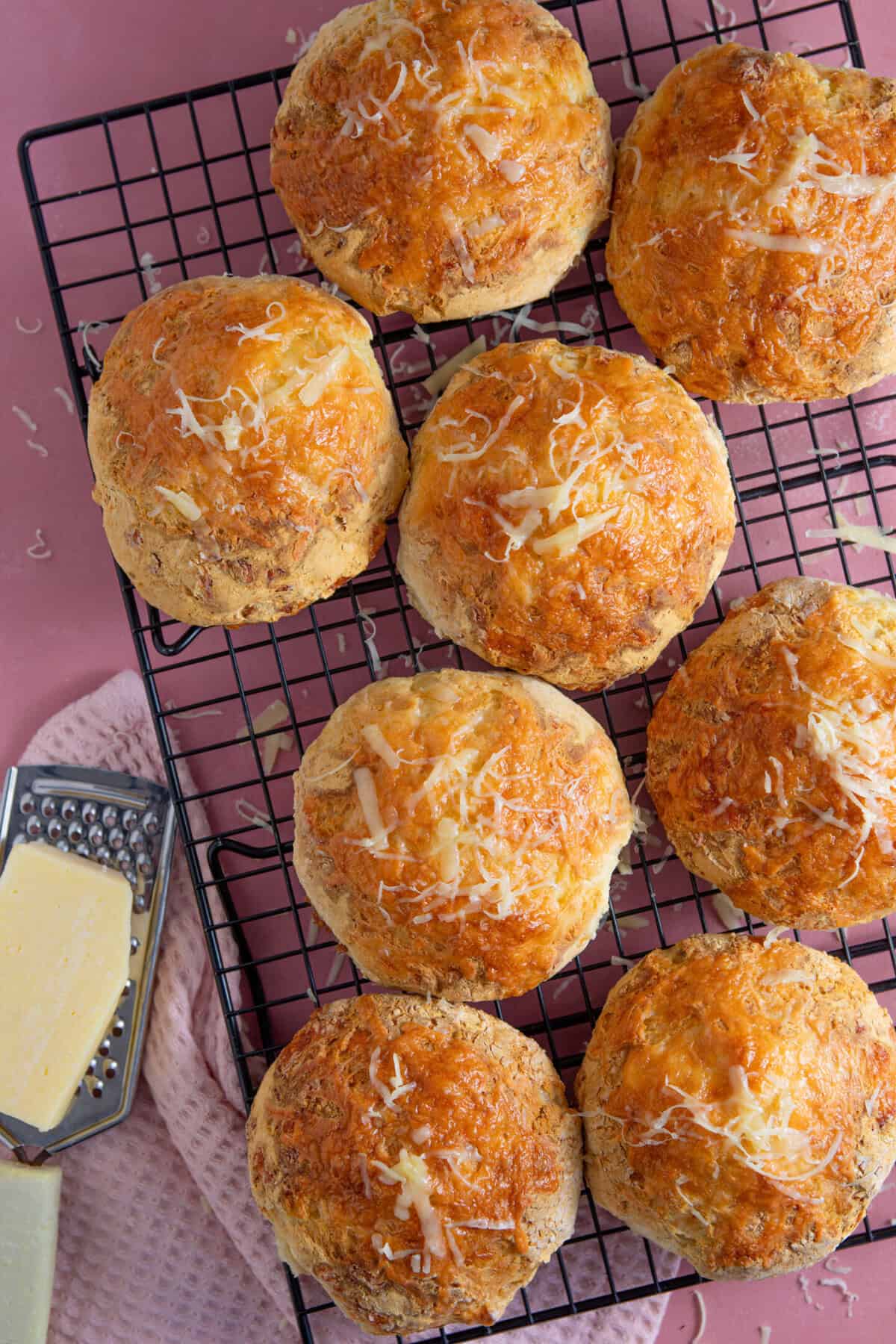 Process shot of gluten free cheese bread rolls showing the finished rolls on a cooling rack.