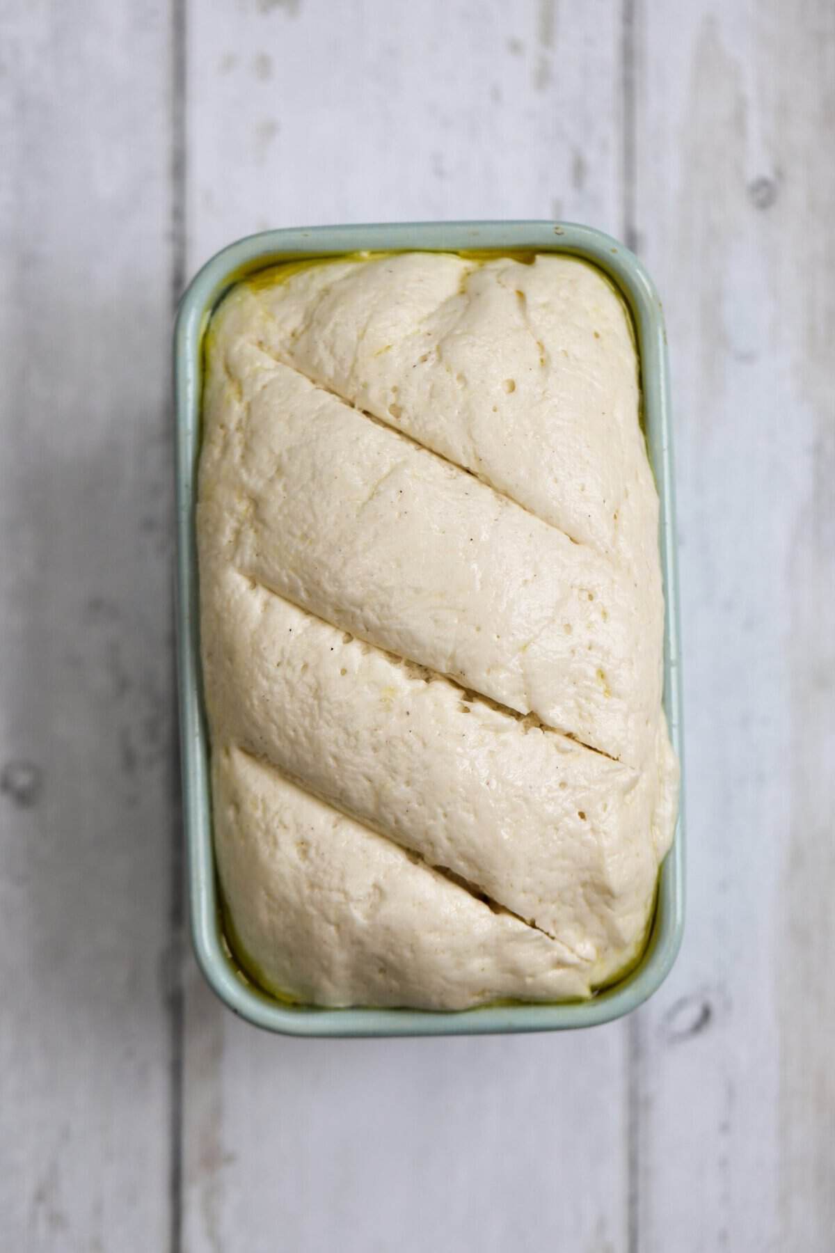 Process shot of 5-ingredient gluten free bread recipe showing the bread dough risen to the top of the tin.