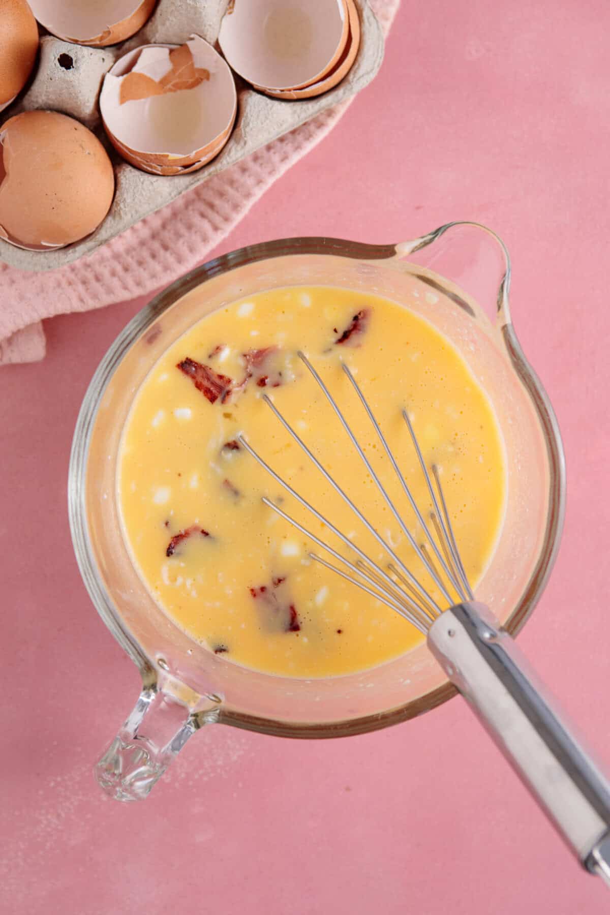 Process shot of cottage cheese egg bites recipe showing the eggs, cottage cheese, mozzarella and bacon in a jug after mixing.