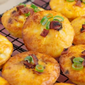 Close up of cottage cheese egg bites on a wire rack with cheese and bacon.