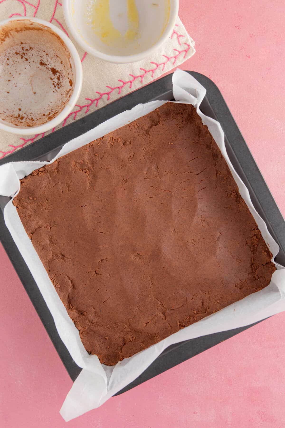 Process shot for gluten free chocolate concrete recipe showing the mixture pressed into a baking tin.