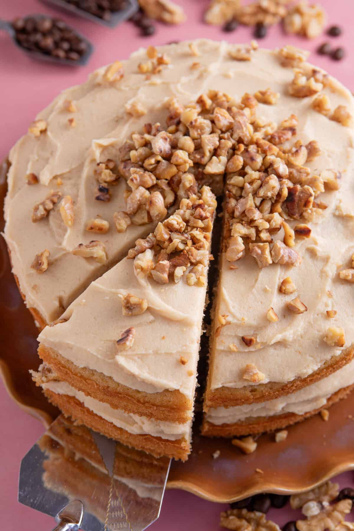 A gluten free coffee and walnut cake with a slice cut from it.