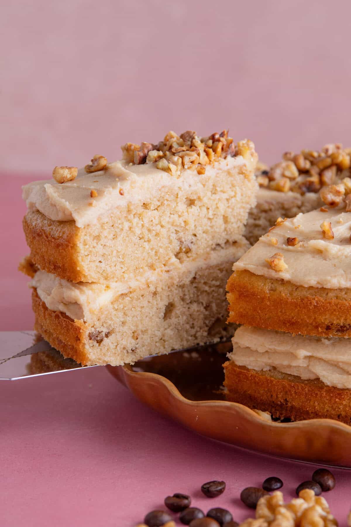 A slice of gluten free coffee and walnut cake being served up.