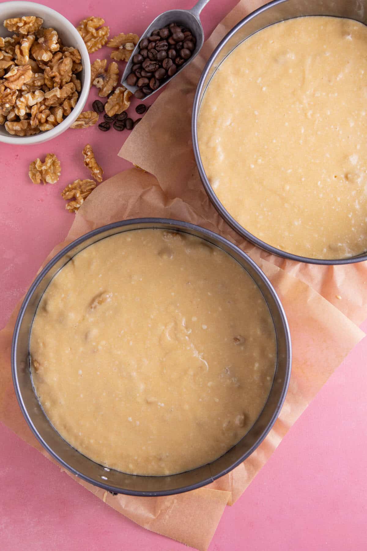 Process shot for gluten free coffee and walnut cake showing the cake batter portioned between baking tins.