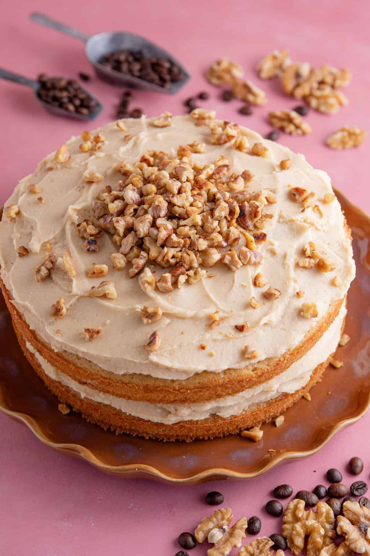 Process shot for gluten free coffee and walnut cake showing the finished cake decorated with walnuts.