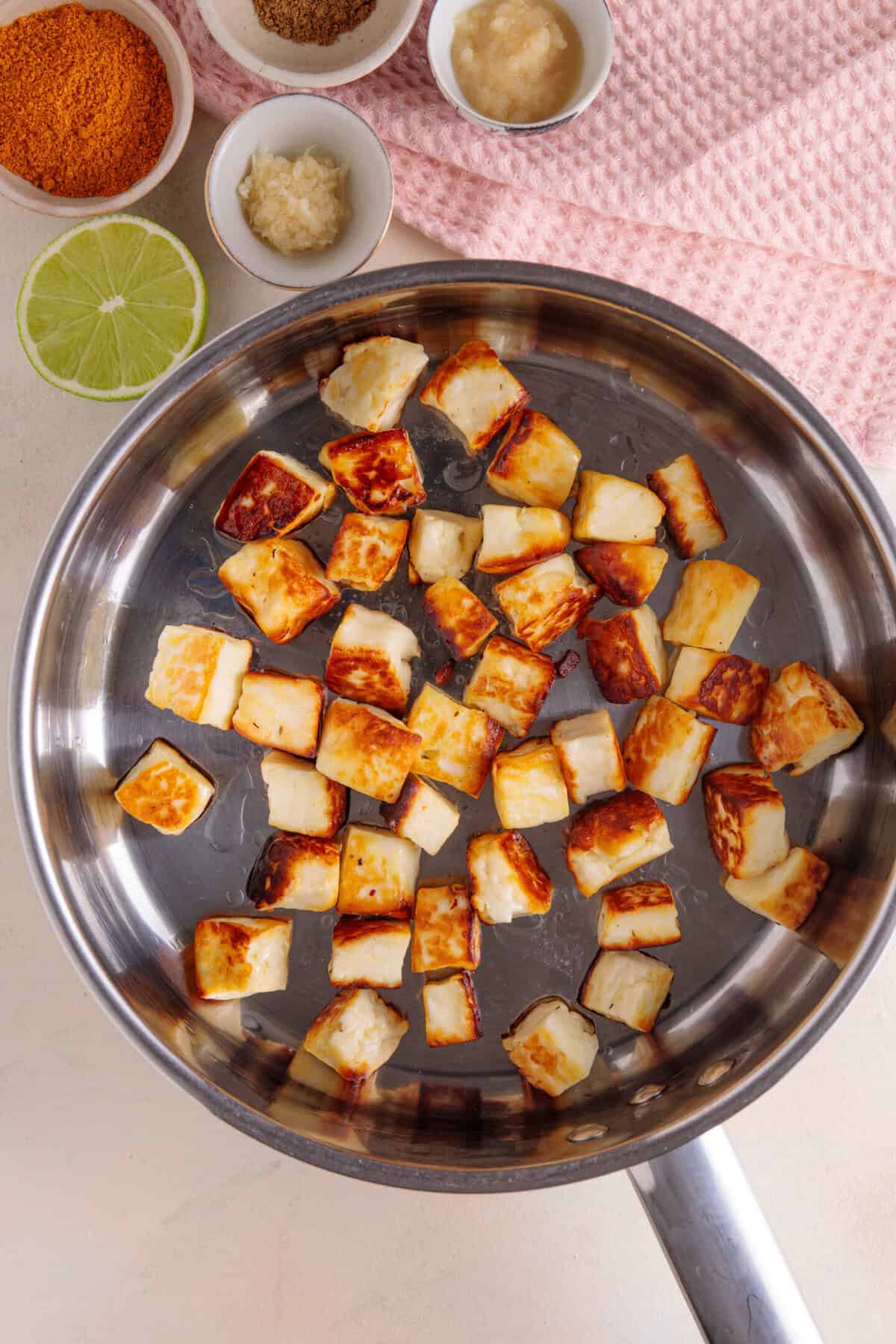 Process shot for halloumi curry showing the halloumi cubes frying in a pan.