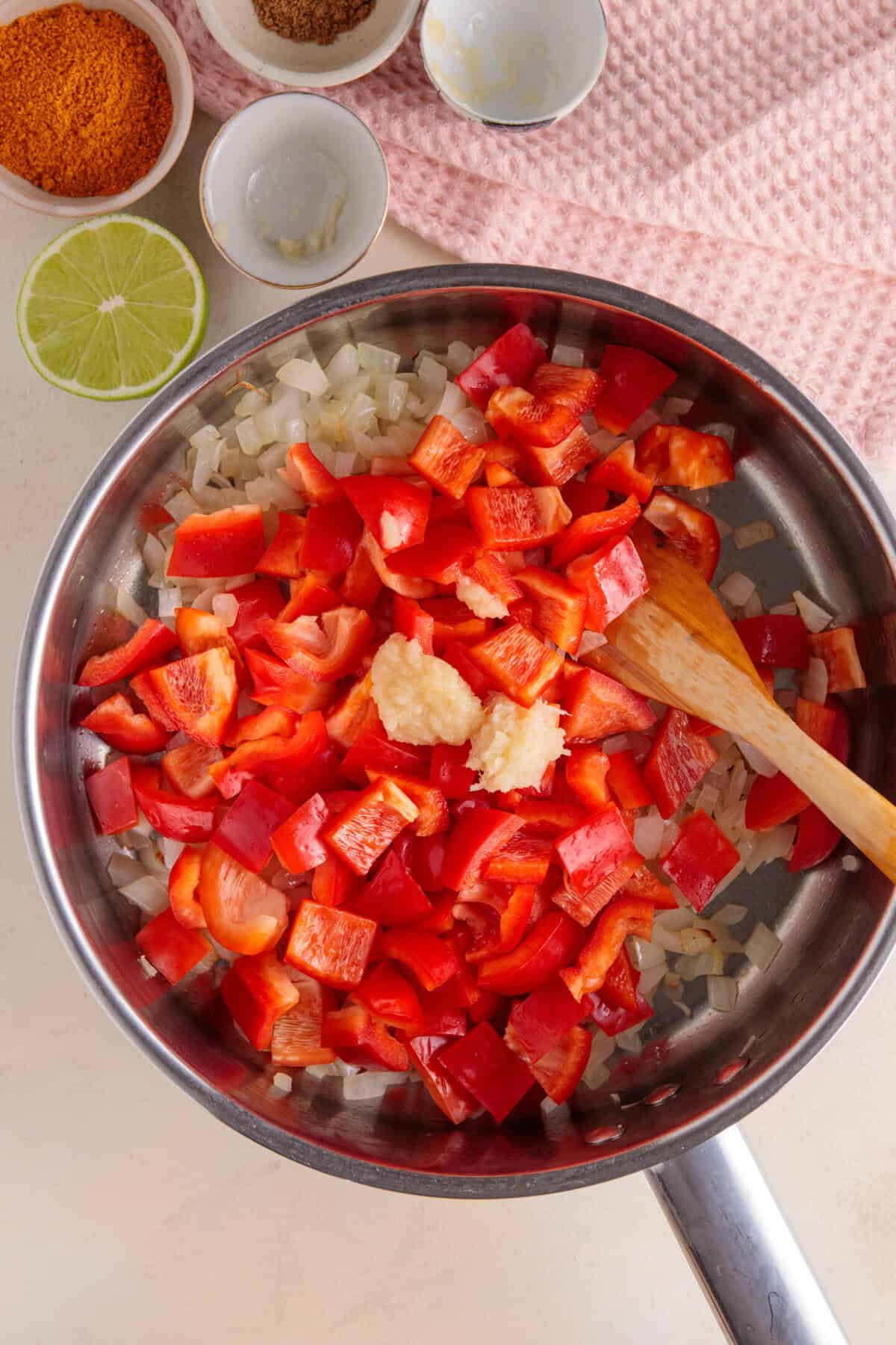 Process shot for halloumi curry showing the onions, peppers, garlic and ginger frying in a pan.