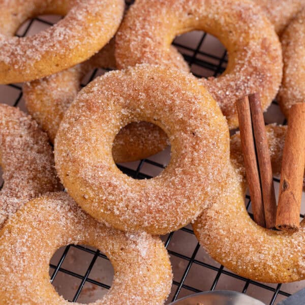 Close up of a pile of pumpkin donuts with cinnamon sugar.