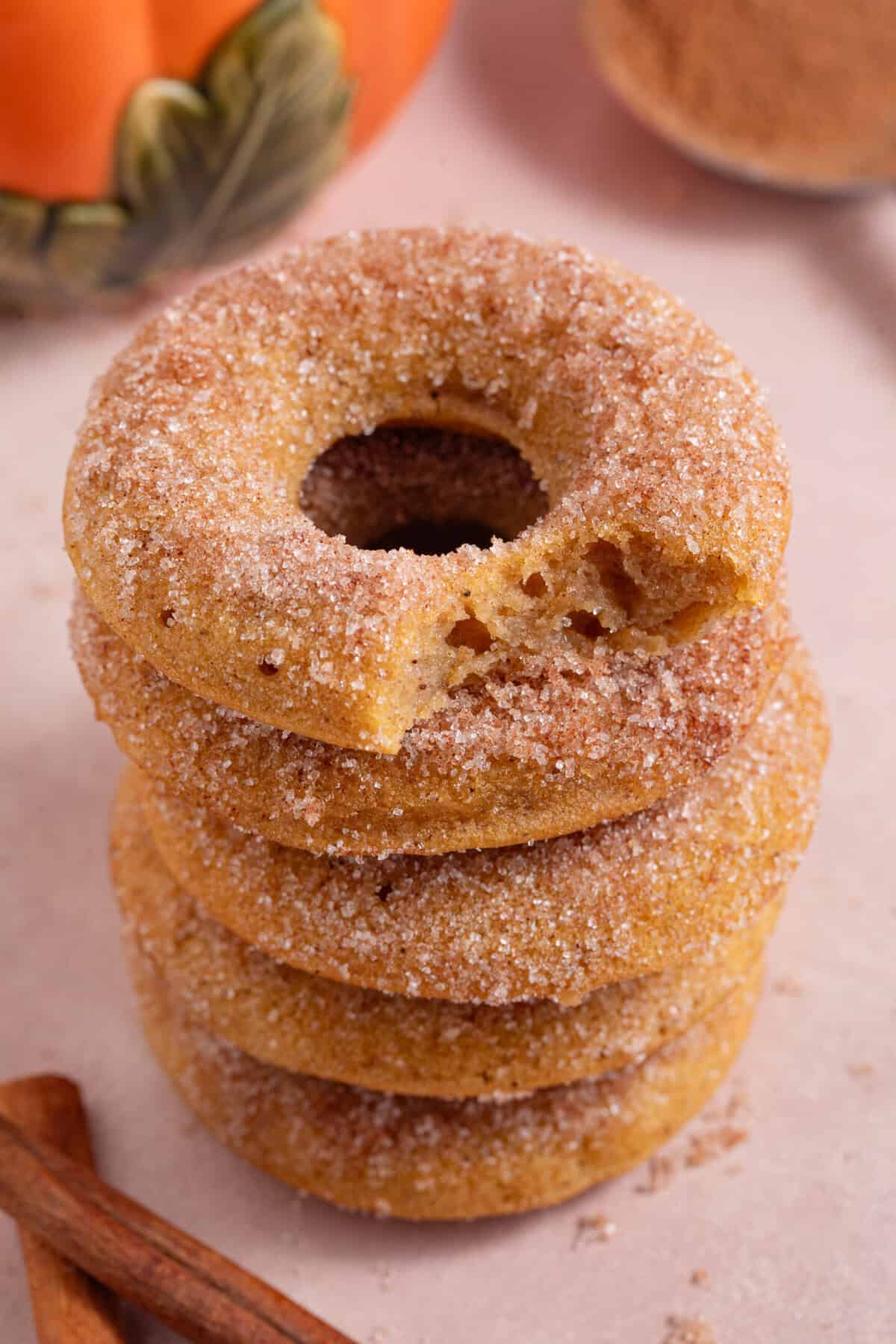 A stack of pumpkin donuts with a bite taken out of one.