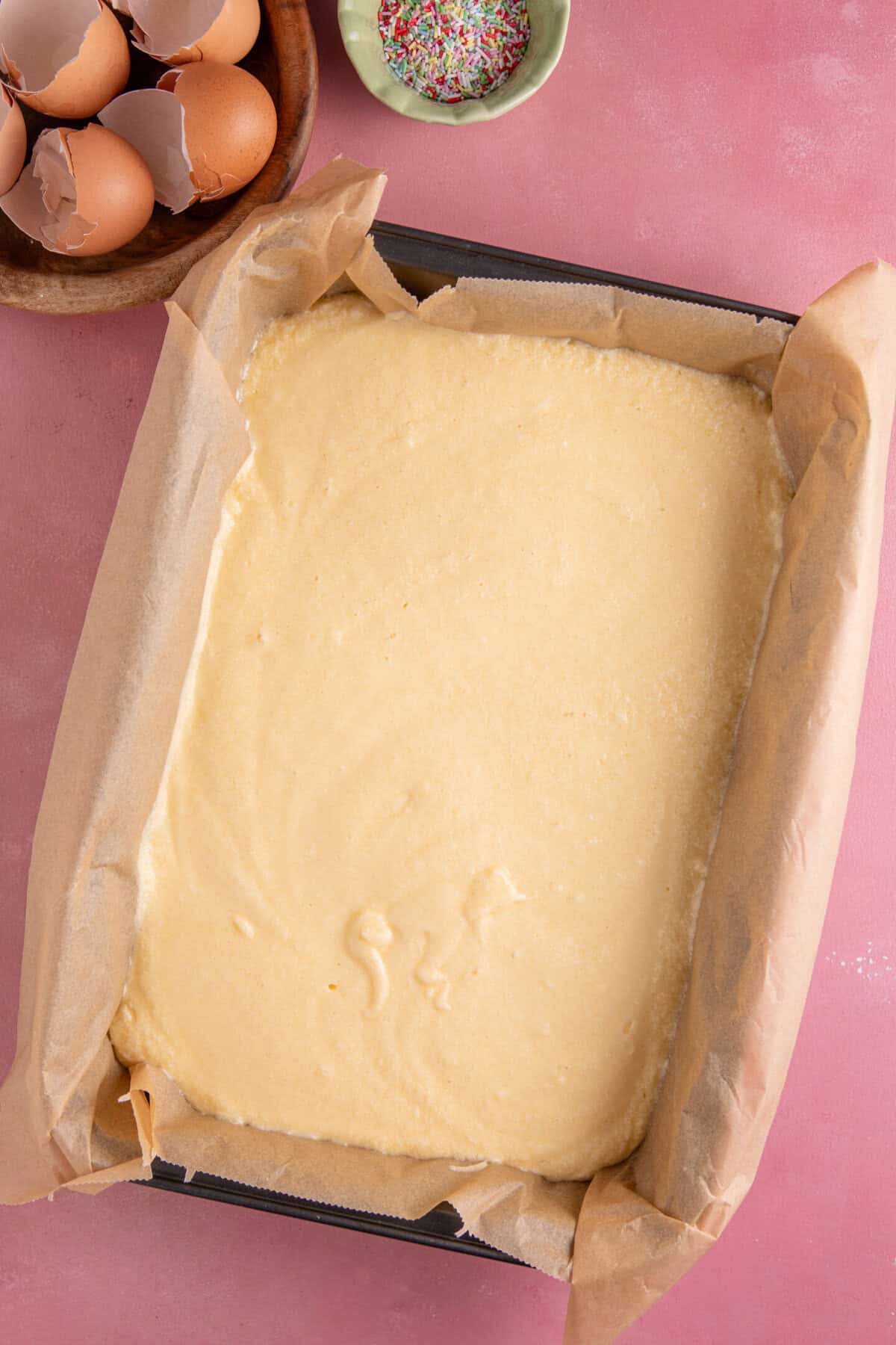 Process shot for gluten free school dinner cake showing the cake batter in a lined pan before baking.