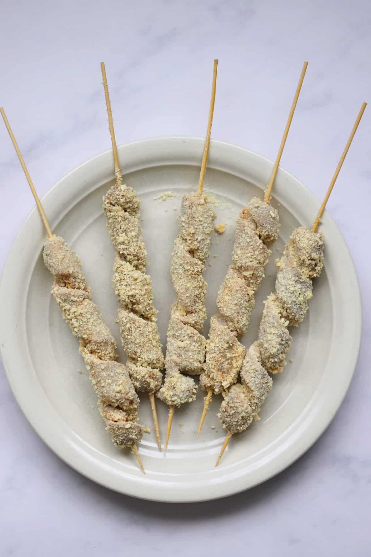 Process shot of gluten free turkey twizzlers showing a plate of turkey spirals coated in gluten free breadcrumbs.