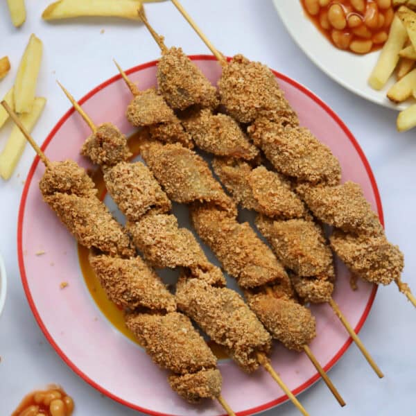 A plate of gluten free turkey twizzlers with chips and beans on the side.