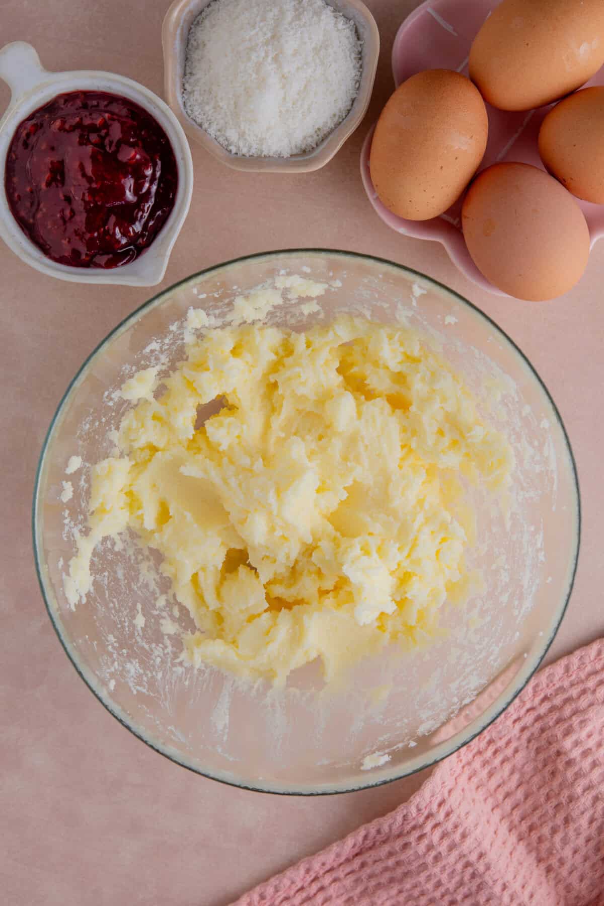Process shot of jam and coconut sponge showing the butter and sugar creamed together in a mixing bowl.
