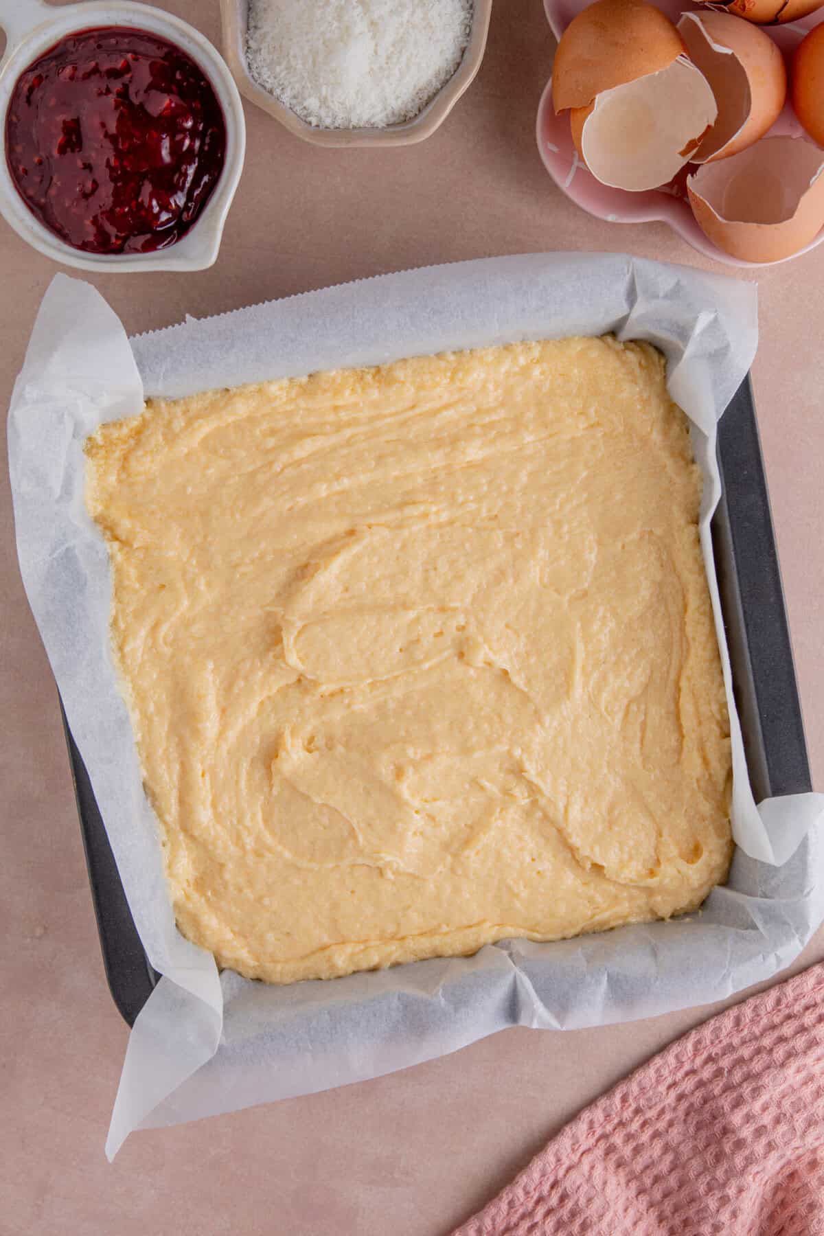 Process shot of jam and coconut sponge showing the cake batter in the lined baking tin.