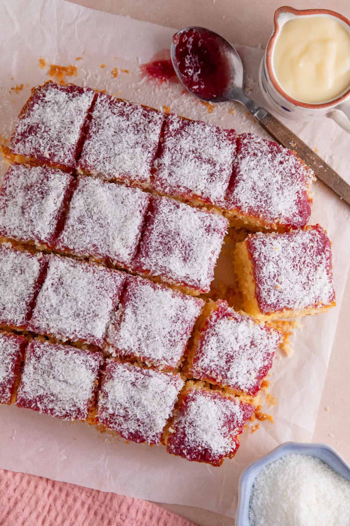 Process shot of jam and coconut sponge showing the finished cake topped with coconut and cut into squares.