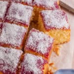 A gluten free jam and coconut sponge cake cut into squares.