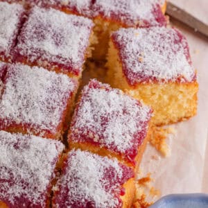 A gluten free jam and coconut sponge cake cut into squares.