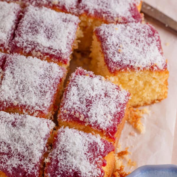 A gluten free jam and coconut sponge cake cut into squares.
