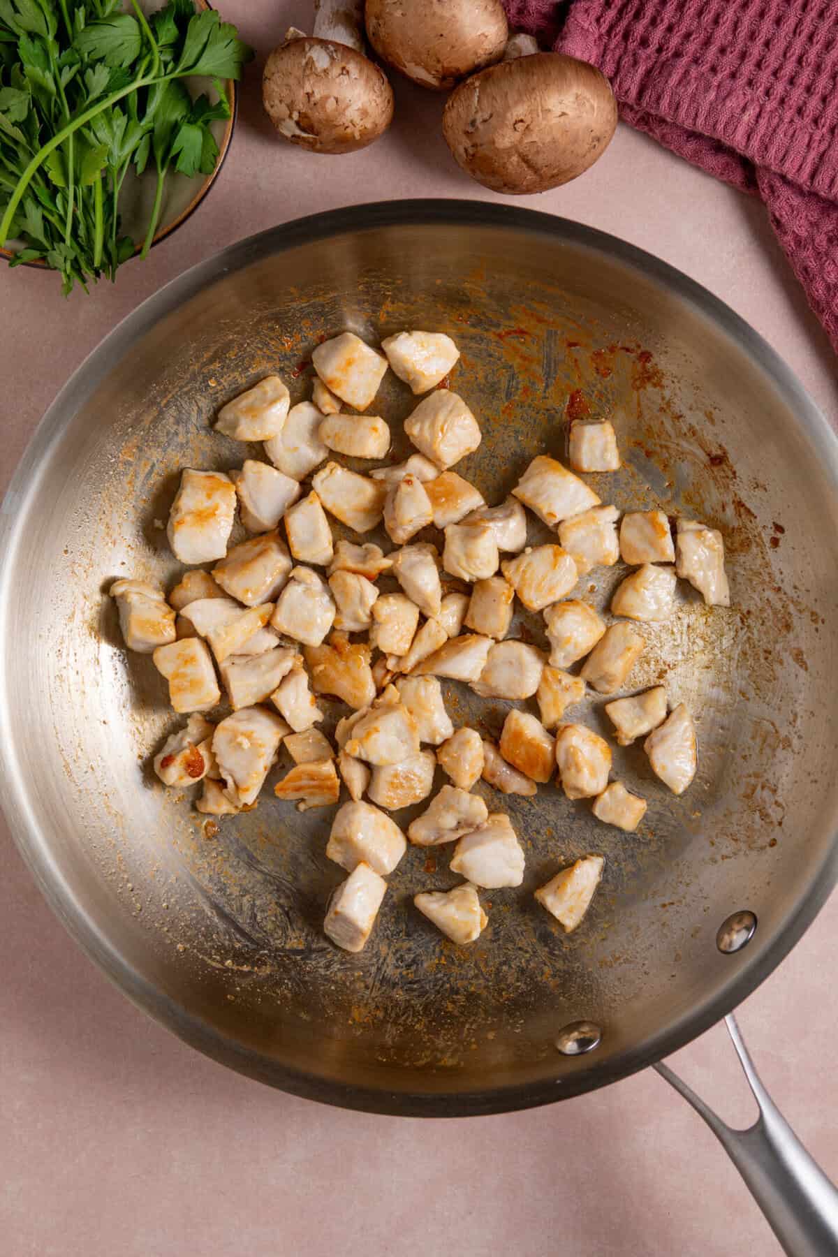 Process shot for gluten free chicken stroganoff showing the chicken frying in a pan.