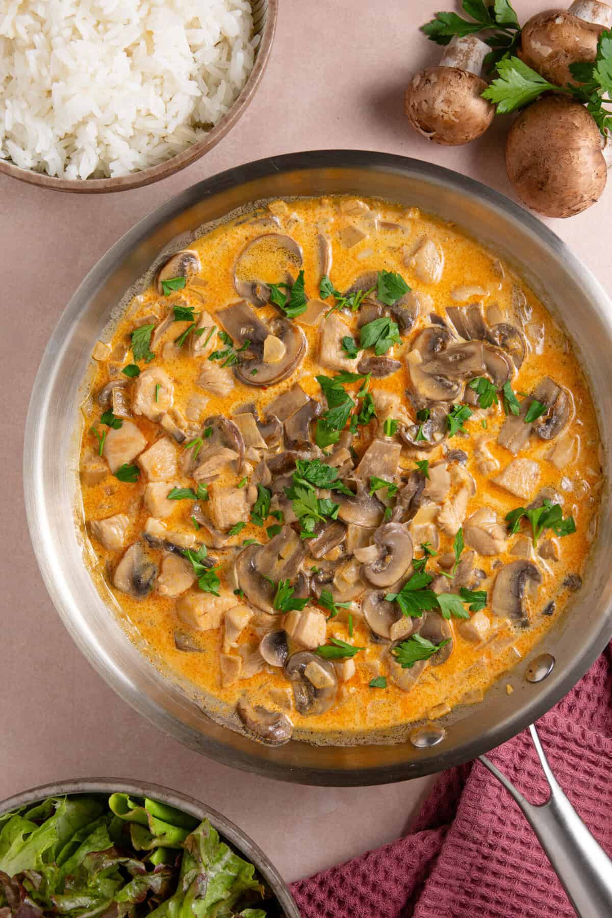 A pan of chicken stroganoff garnished with fresh parsley.