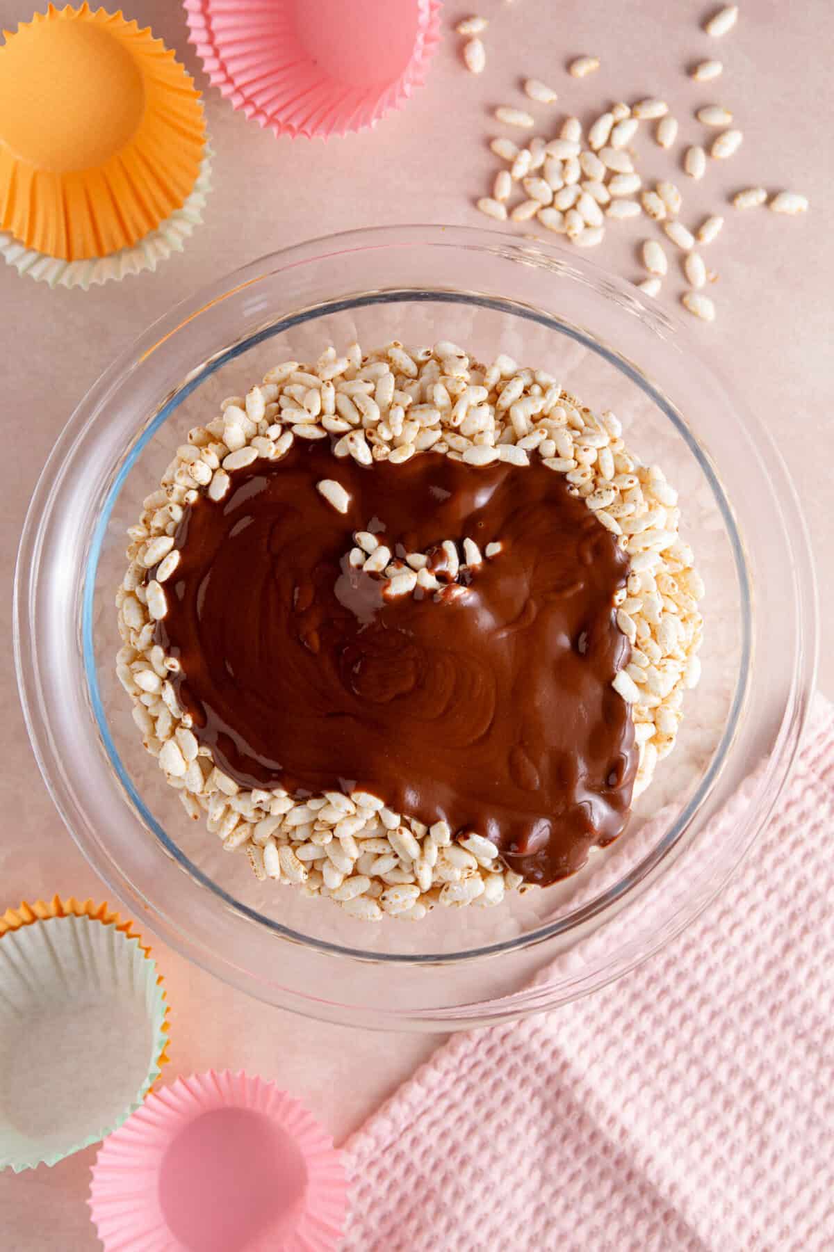 A glass bowl with puffed rice and melted chocolate poured on top.