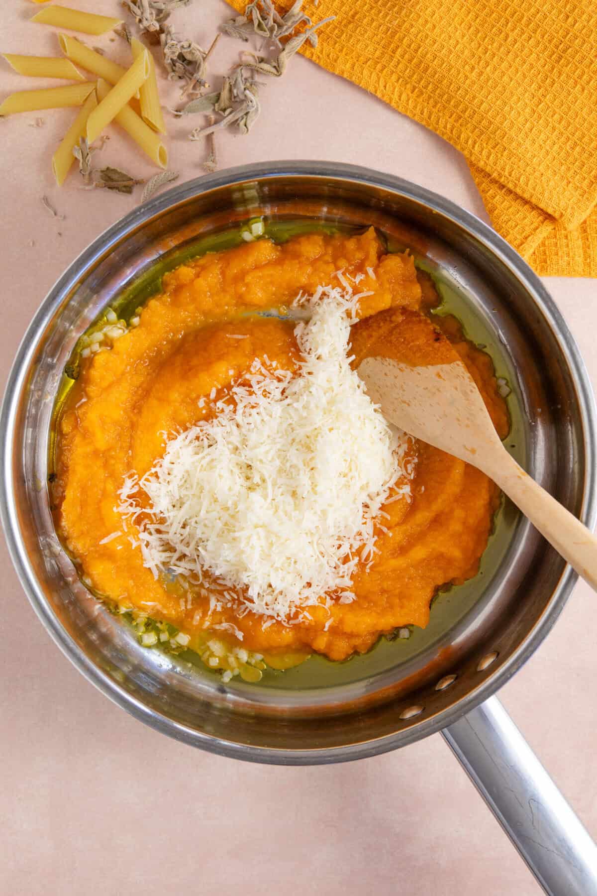Process shot for creamy pumpkin pasta showing the pumpkin and parmesan added to the pan.
