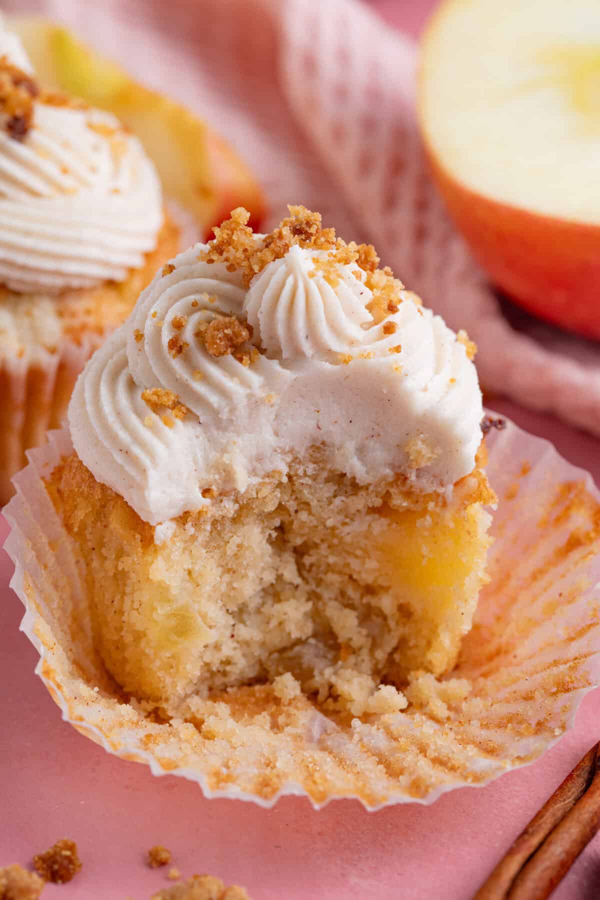A gluten free apple crumble cupcake with a bite taken out of it.