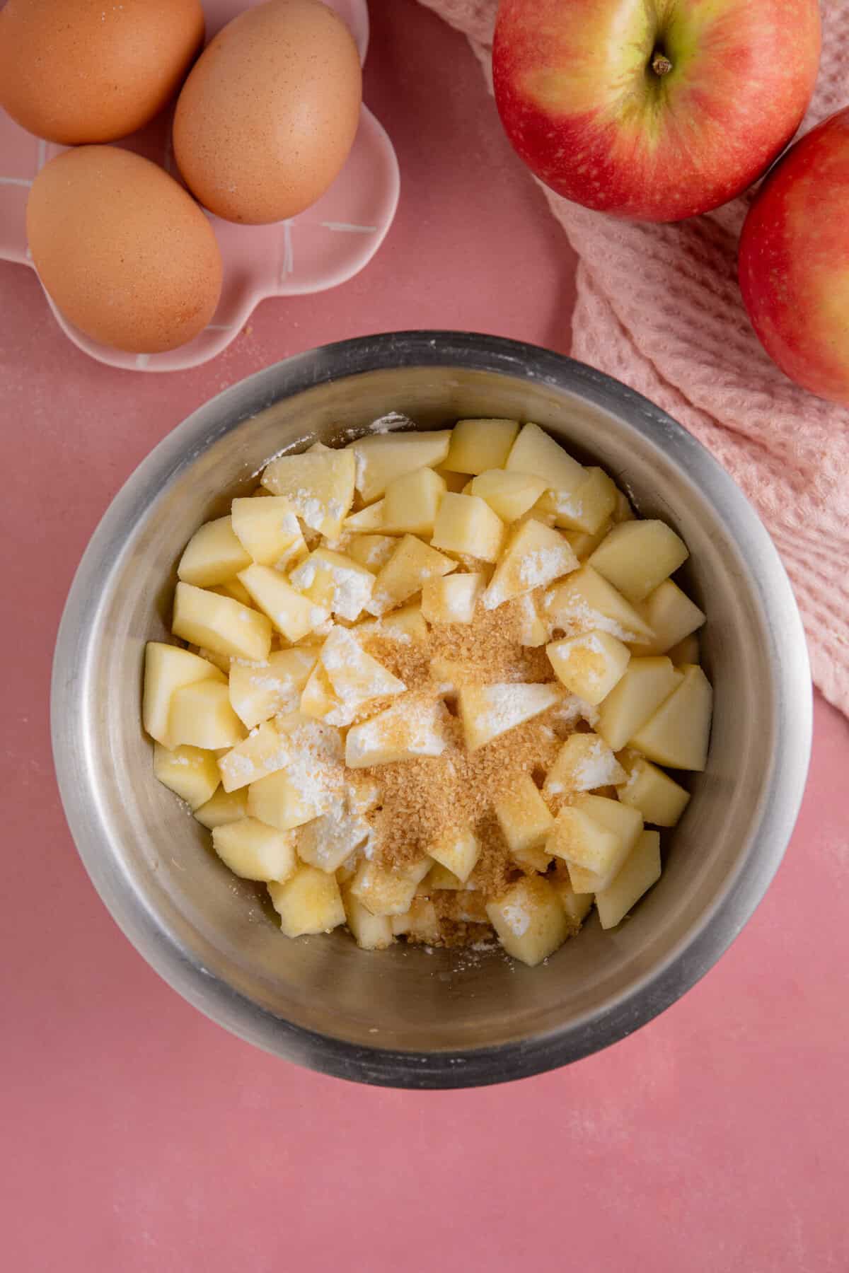 Process shot of gluten free apple crumble cupcakes showing the chopped apples and sugar in a mixing bowl.