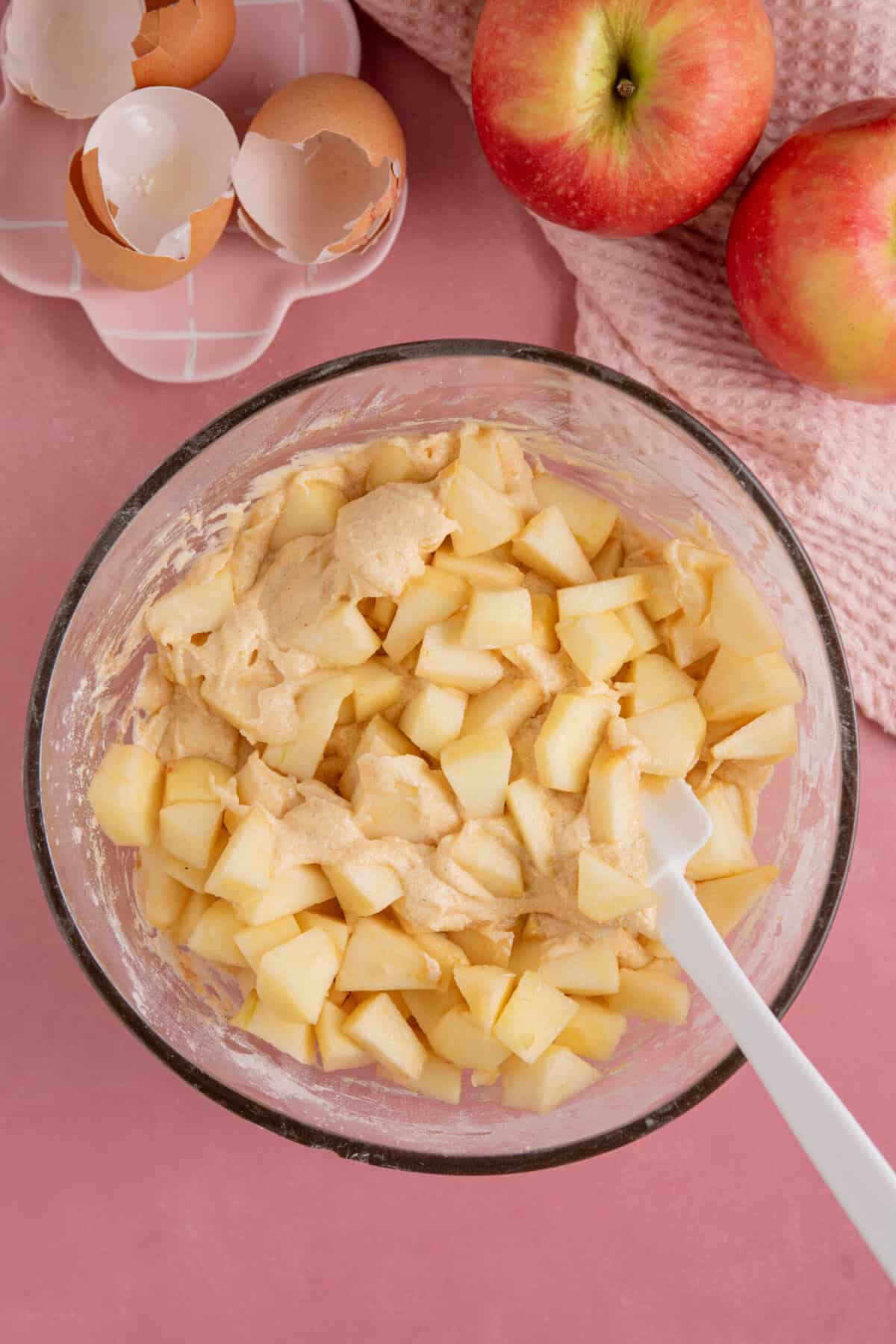Process shot of gluten free apple crumble cupcakes showing the apple chunks being folded into the cake batter.