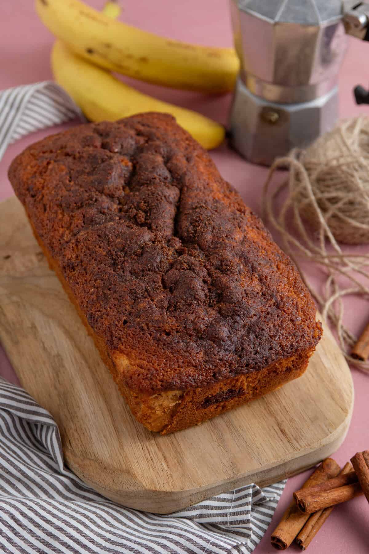 Process shot of cinnamon swirl banana bread showing the finished banana bread on a wooden board.