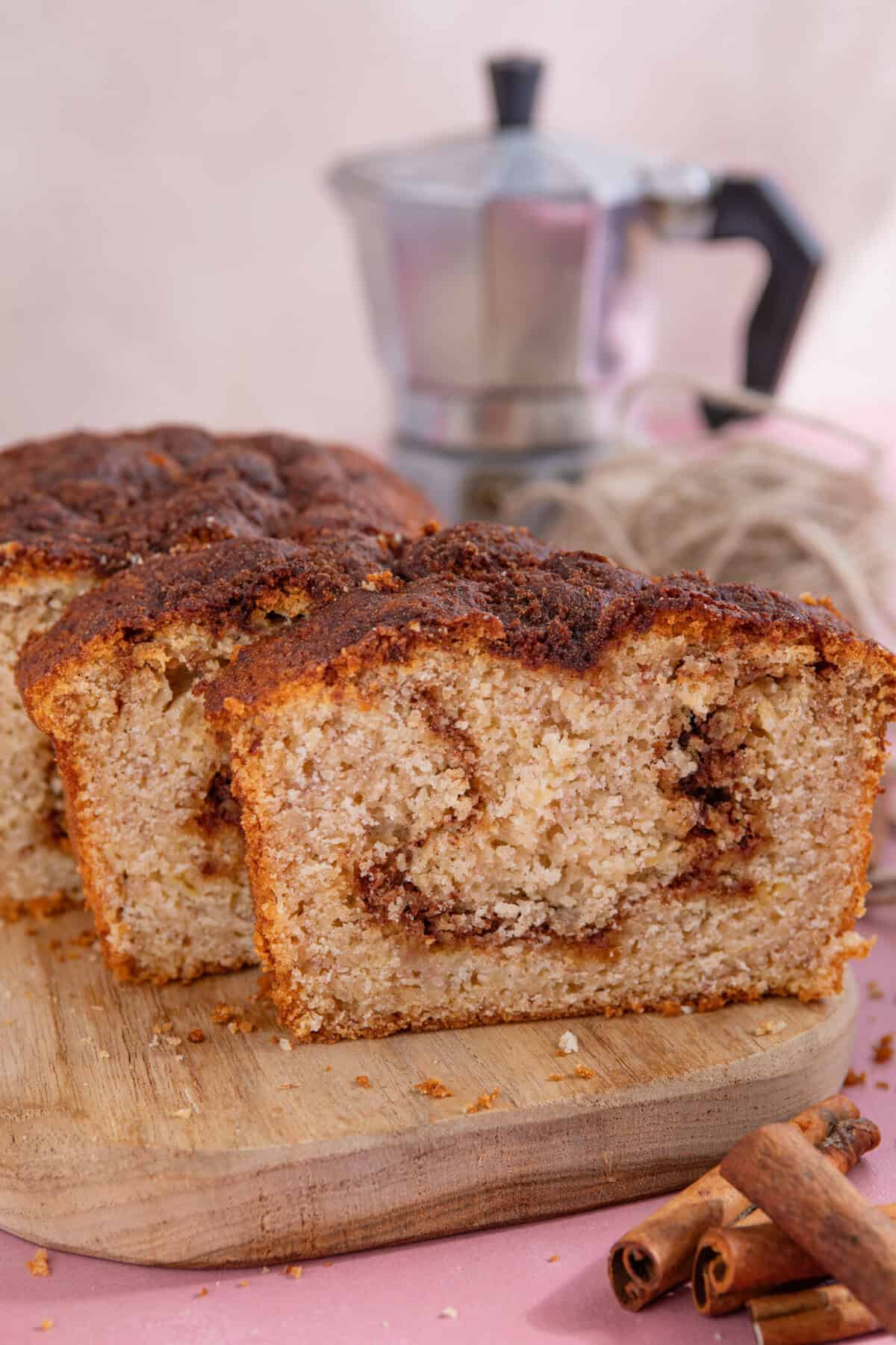 Slices of gluten free cinnamon swirl banana bread with a coffee pot outside.