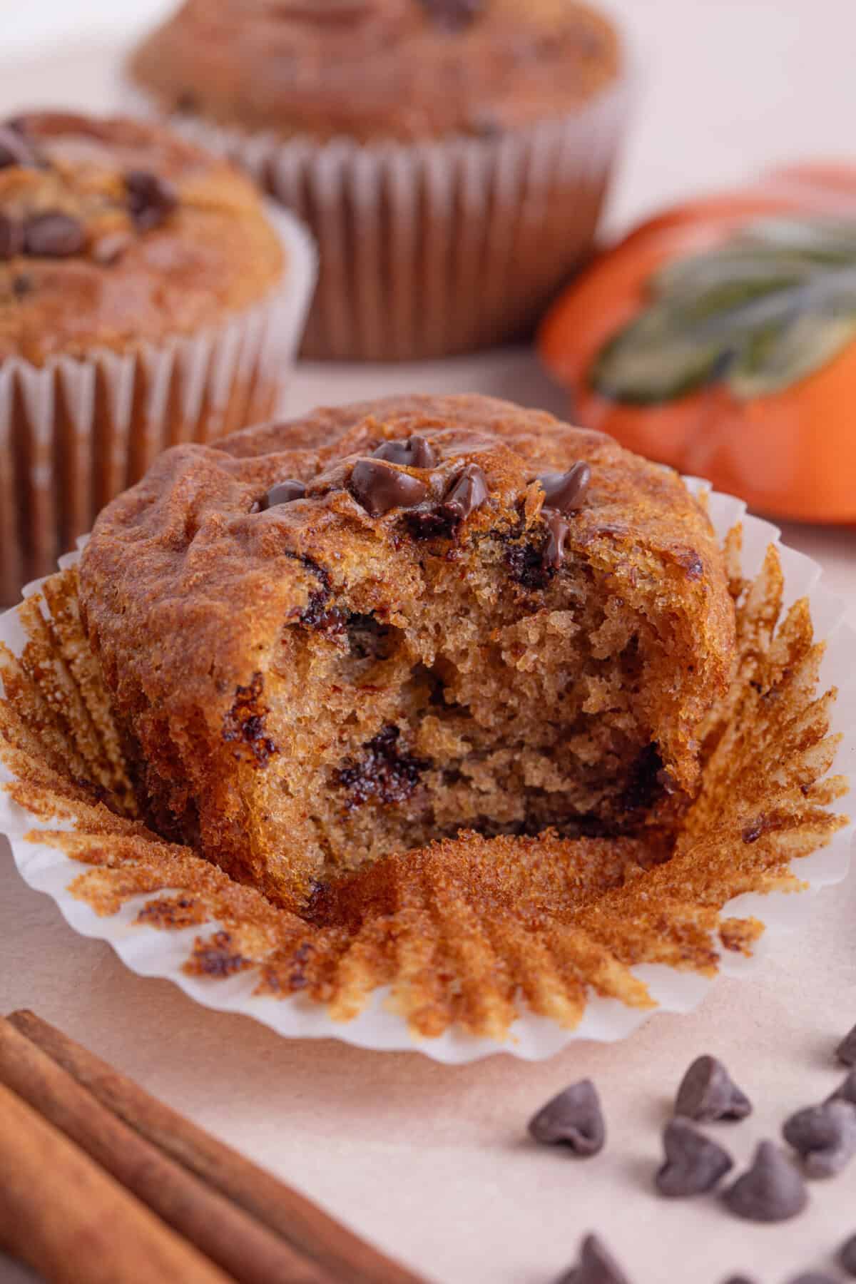 A pumpkin chocolate chip muffin with a bite taken out of it.