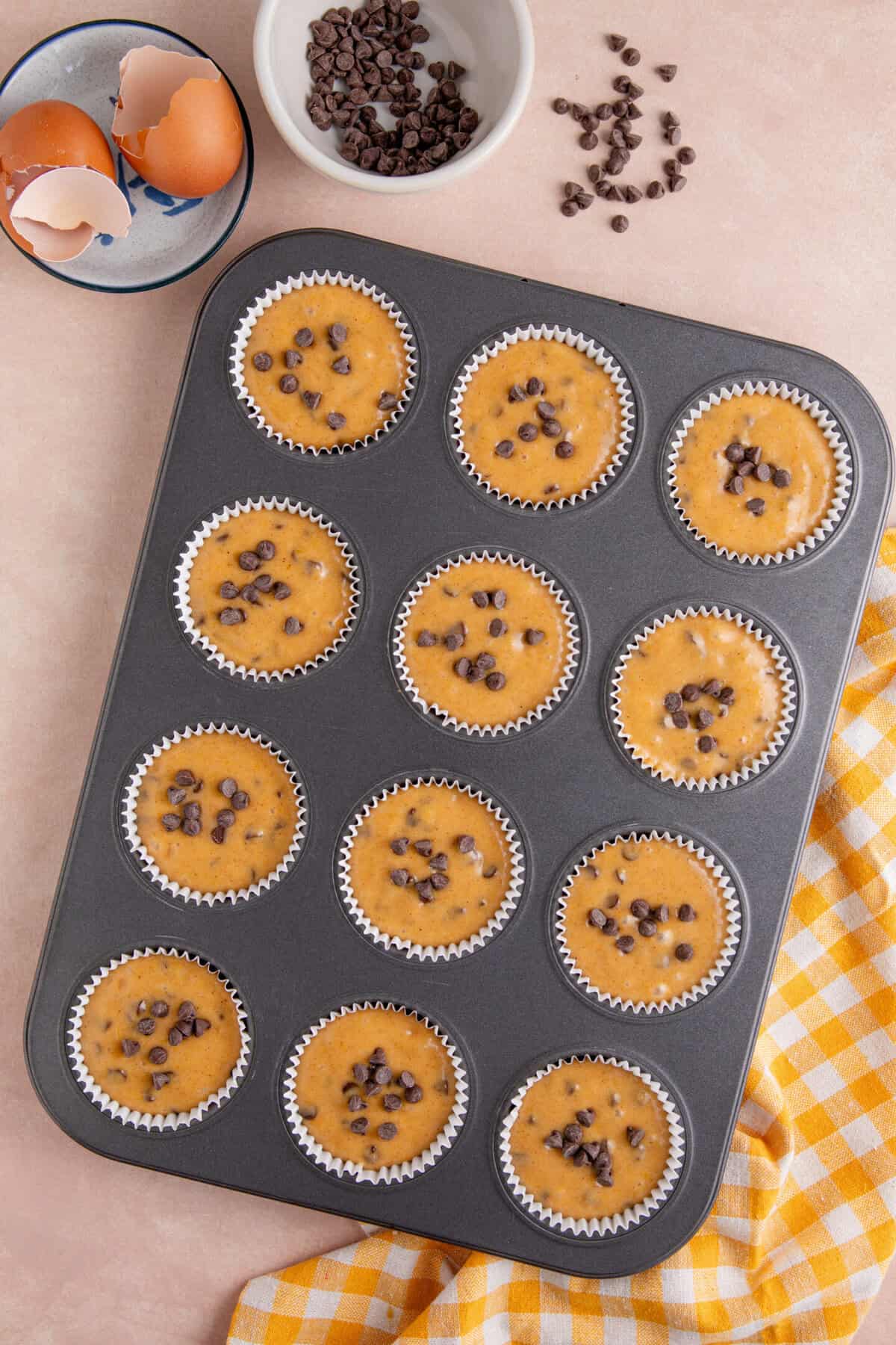 Process shot for gluten free pumpkin chocolate chip muffins showing the muffin batter shared between the tins.