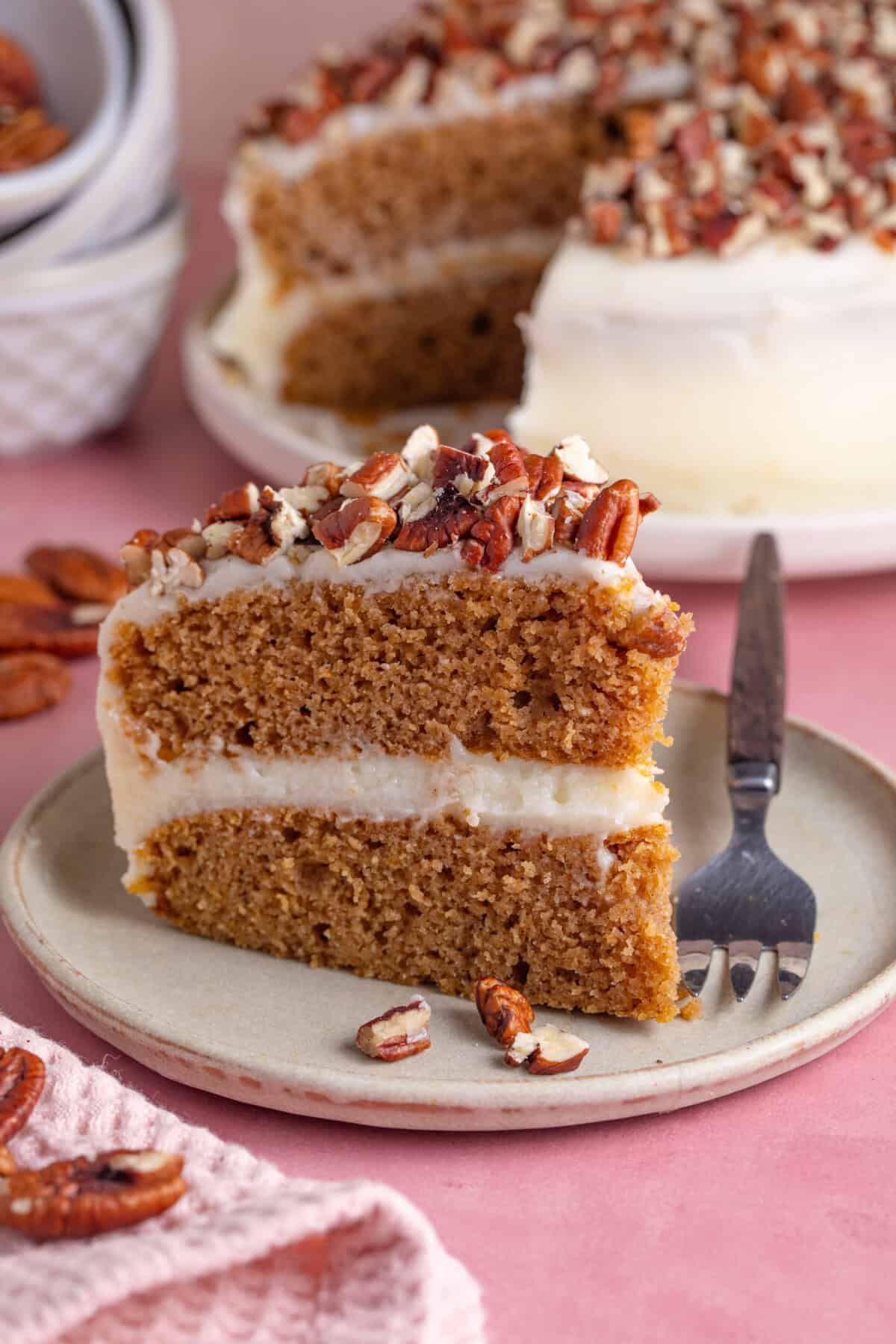 A slice of gluten free pumpkin spice latte cake with the rest of the cake behind.