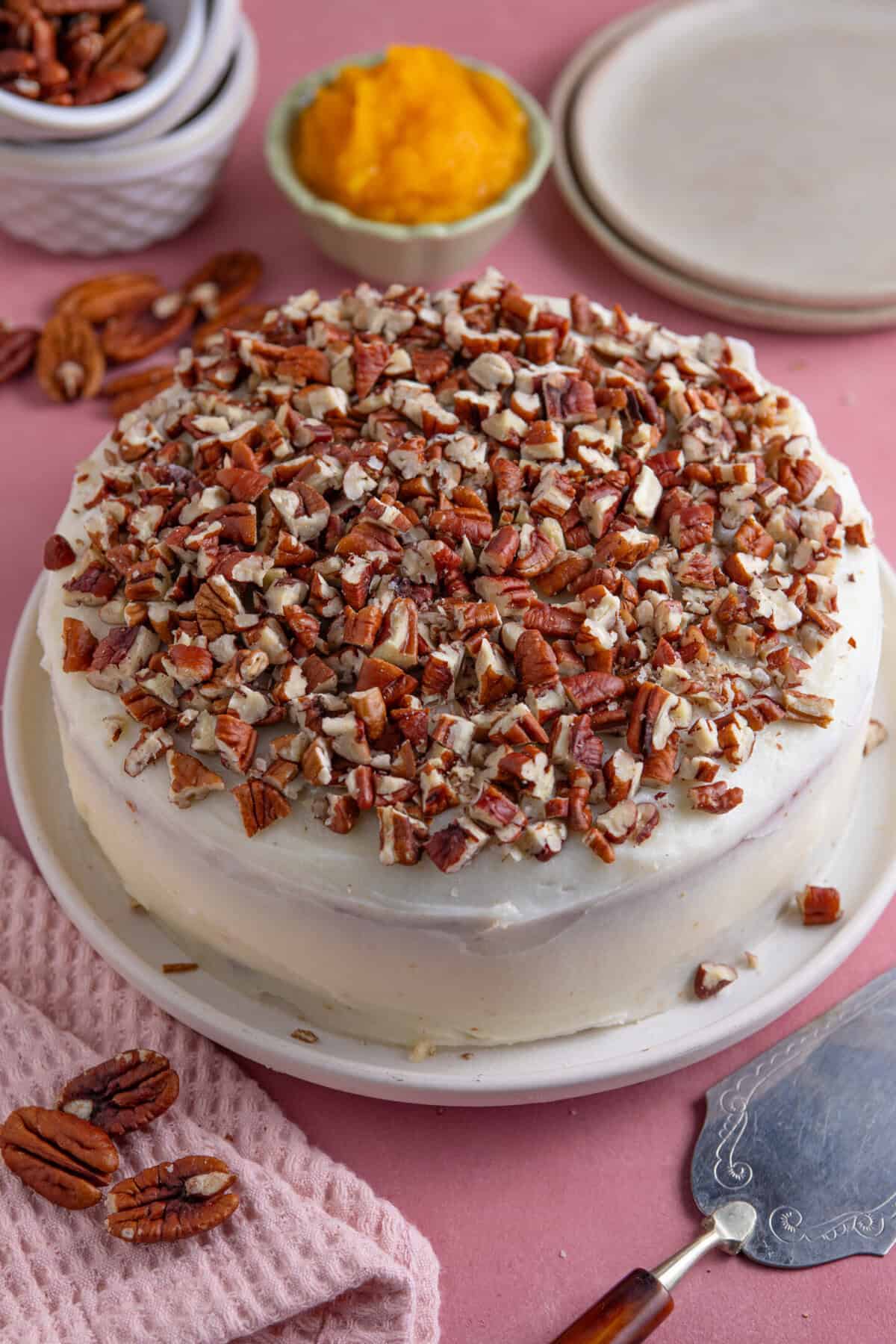 A gluten free pumpkin spice latte cake with cream cheese frosting and pecans on top.
